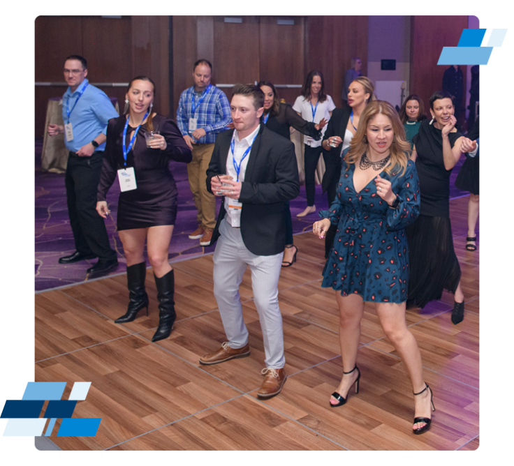 DBP_22MIS1_20220807_M2229 1 Amidst the lively rhythms, a group of people enjoys the dance floor at an indoor event. With drinks in hand and lanyards around their necks, it hints at a conference where freight agent opportunities abound. The wooden flooring adds warmth to the vibrant atmosphere.