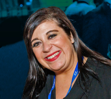 jennifer_mattos A smiling Logistics Agent with long, dark hair wears a black top and a blue lanyard.